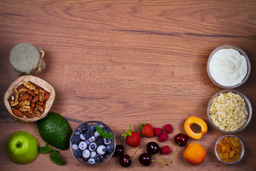 Bowls of Yogurt and Oat Flakes, Fruits, Honey and Summer Berries. View from above, top studio shot of fruit background. Flat lay setup made of selection of healthy food, copy space