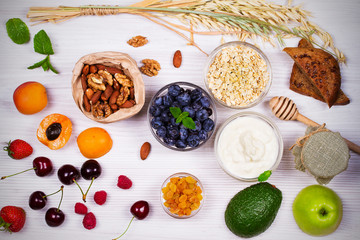Bowls of Yogurt and Oat Flakes, Fruits, Honey and Summer Berries. View from above, top studio shot of fruit background. Flat lay setup made of selection of healthy food, copy space