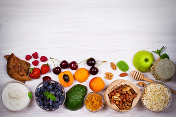 Bowls of Yogurt and Oat Flakes, Fruits, Honey and Summer Berries. View from above, top studio shot of fruit background. Flat lay setup made of selection of healthy food, copy space
