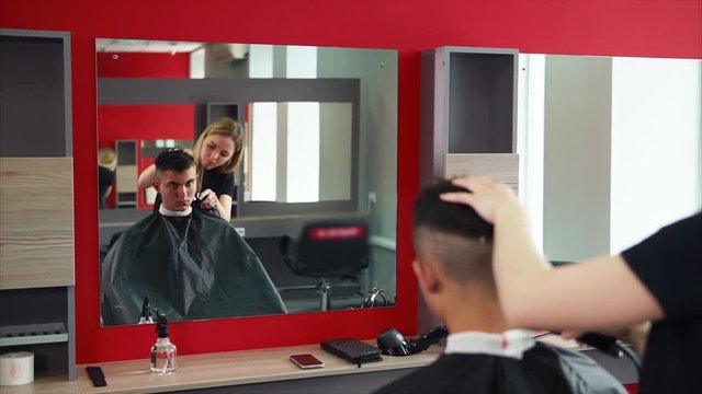 The blonde hairdresser cuts her hair with an electric razor, a man who came to a beauty salon and sits in front of a mirror expects a change of image and good service