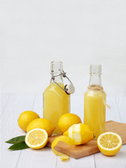Freshly squeezed lemon juice in bottle and lemons on light background. For vitamin drink or cocktail. Selective focus. Space for text.