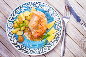 Rabbit with potatoes and lemon in cream sauce, garnished with tarragon. View from above, top studio shot