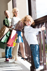 little blond boy standing on balcony with parents behind