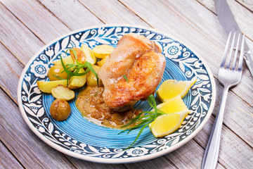 Rabbit with potatoes and lemon in cream sauce, garnished with tarragon