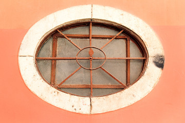 Round window with iron bars. Old ancient metal window. Round and arched window with wrought iron bars in a classic style.