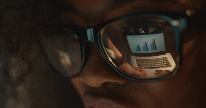 The reflection of the business graphics in the eyeglasses of the afro-american woman.