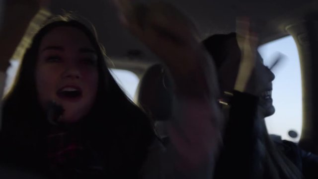 Fun Teen Girls Practice Funny Dance Moves Together In Back Seat Of Moving Car At Night