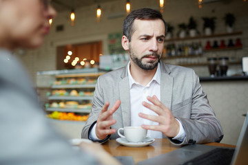 Professional traders explaining online data to co-worker in cafe