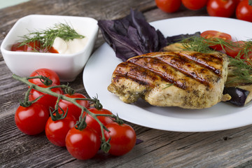Chicken steak with grilled vegetables, tomatoes, oregano, on wooden background