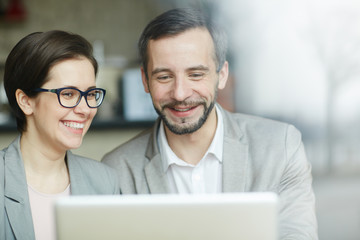 Happy economists reading online data in laptop