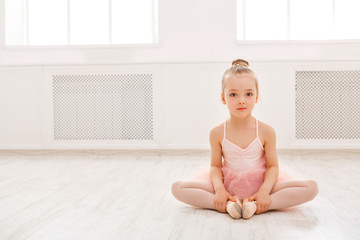 Fototapeta premium Portrait of little ballerina on floor, copy space
