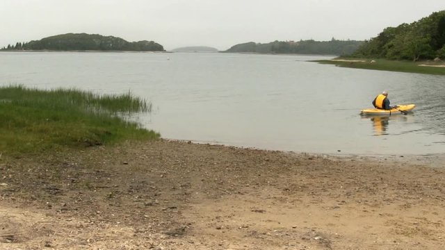 Elderly male kayaker gets comfortable before heading out into lagoon at Bennets Neck Pocasset Bourne Cape Cod