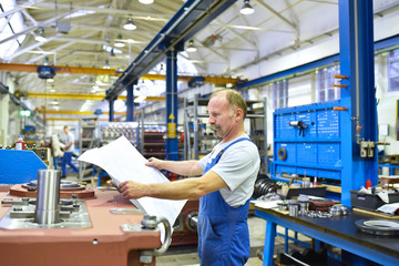 Monteur im Maschinenbau studiert technische Zeichnung für die Montage von Getrieben // Mechanical...