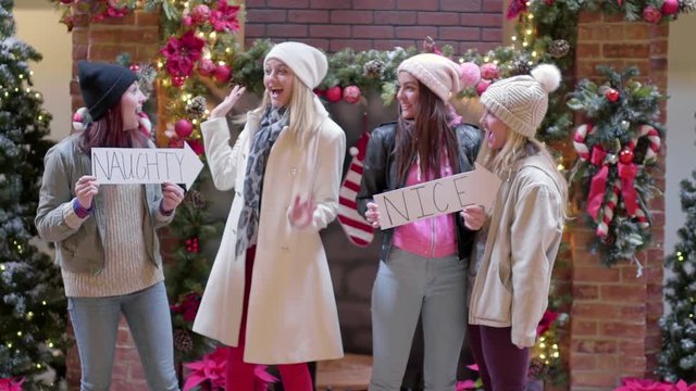 Group Of Fun Teens Pose With "Naughty And Nice" Signs At Mall For Christmas Pictures, "Naughty" Girl Gives Friend Bunny Ears