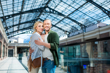 Portrait of smiling couple looking at camera hugging each other at shopping mall