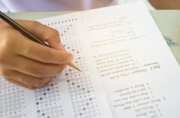 Obraz premium Blurred of student testing english exam or exercise on exams answer sheets with pencil in class room at high school or college, education concept