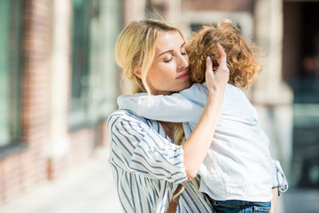 Fototapeta premium portrait of sensual mother with eyes closed hugging little son