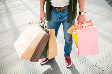 cropped shot of man standing and holding shopping bags in hands
