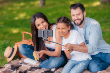 selective focus of family taking selfie with monopod on picnic