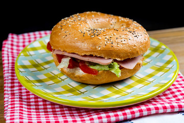 Bagel with fresh cheese and fresh lettuce on napkin