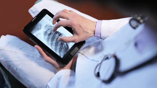 Doctor looks at the x-ray on the tablet