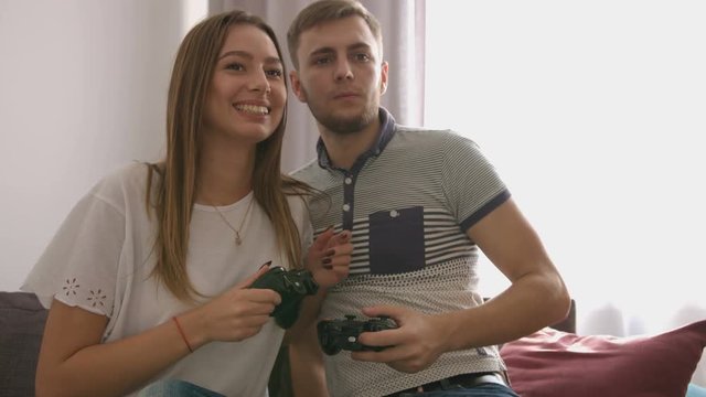 Portrait of couple in love who playing video game while sitting on sofa. Close up shot.