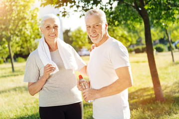 Positive aged couple preparing for sport exercises in the park