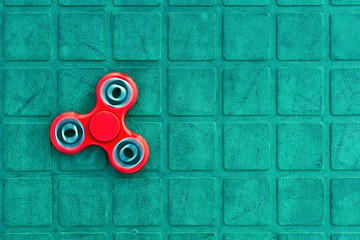 Top view of the popular red spinner gadget in 2017 on the blue-green background