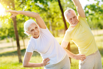 Joyful aged couple training in the park