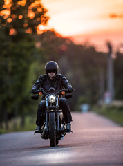 Fototapeta premium Man riding sportster motorcycle during sunset.