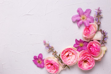 Fresh pink  roses and violet summer clematis flowers on grey textured background.