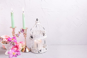 Two birning candles and  summer flowers on grey textured background.