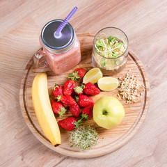 Detox cleanse drink, fruits and berries smoothie ingredients. Natural, organic healthy juice for weight loss diet or fasting day. Mason jar of dietary drink with strawberries, microgreens and banana