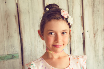 Freckled little girl with flowers in her hair posing in front of white background