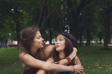 Two happy young girls hug each other in summer park