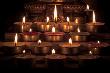 Close Up Group of burning candles in thai style with blurred buddha statue background and concept...