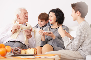 Grandparents eating cake with grandsons