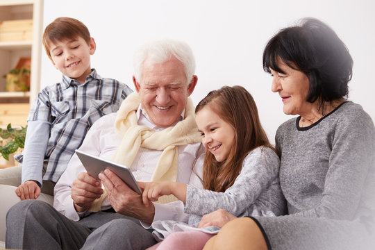 Grandparents and grandchildren using tablet