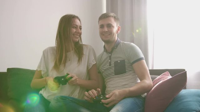 Young attractive couple in love playing video game while sitting on sofa and feeling so happy. Close up shot.