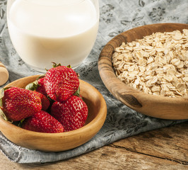 Healthy breakfast concept with oat flakes and fresh berries on rustic background. Food made of granola and musli. Healthy banana smoothie with blackberries, honey and milk.