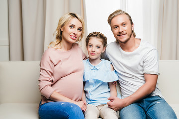 portrait of young smiling family sitting on sofa at home