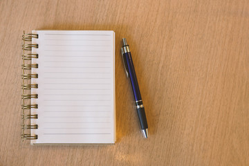 Blank notebook with pen on wooden desk