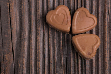 Chocolate heart-shaped candy on wooden background