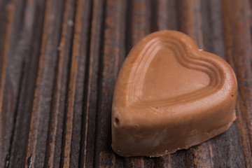 Chocolate heart-shaped candy on wooden background