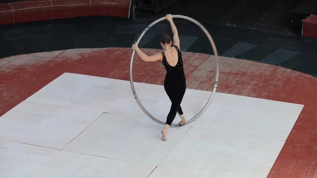 Skilled professional circus artist training with a big cyr wheel on stage