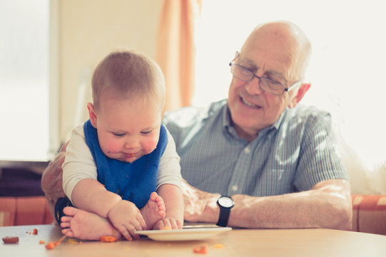 Grandfather helping baby learning to eat solids