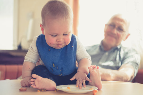 Grandfather helping baby learning to eat solids