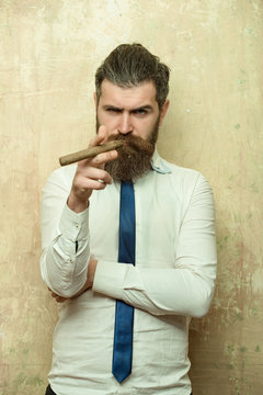 bearded man on serious face smoking cigar