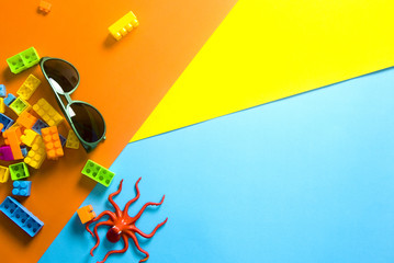 sunglasses with brick toy and octopus on color background