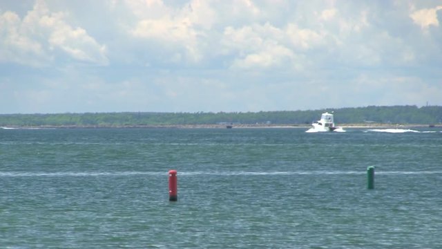 Motor boat cruises through buzzards bay out past channel markers on Cape Cod